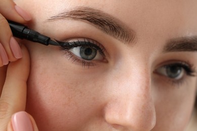 Photo of Makeup product. Woman applying black eyeliner, closeup