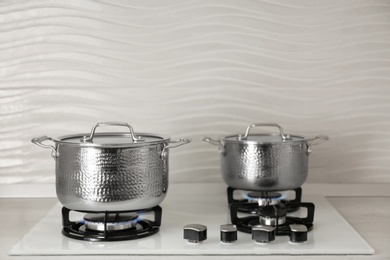 Photo of Shiny steel saucepans on modern gas stove. Space for text