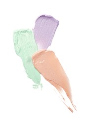 Photo of Strokes of pink, green and purple color correcting concealers isolated on white, top view