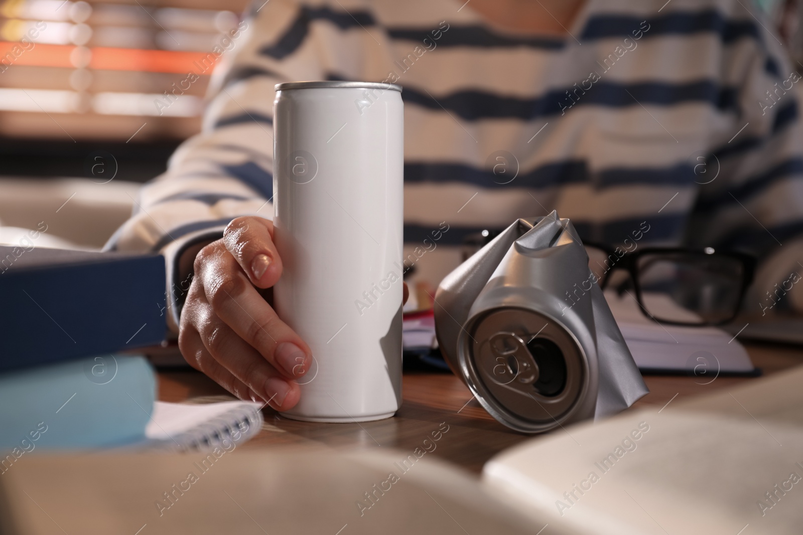 Photo of Young woman with energy drink studying at home, closeup