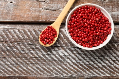 Photo of Aromatic spice. Red pepper in bowl and spoon on wooden table, top view. Space for text