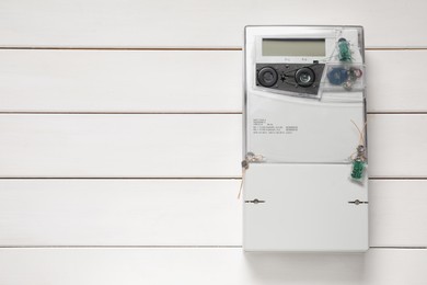 Photo of Electricity meter on white wooden wall, space for text