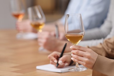 Photo of Sommeliers tasting different sorts of wine at table indoors, closeup