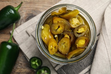 Photo of Fresh and pickled green jalapeno peppers on wooden table, flat lay