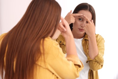 Photo of Woman with skin problem looking at mirror indoors