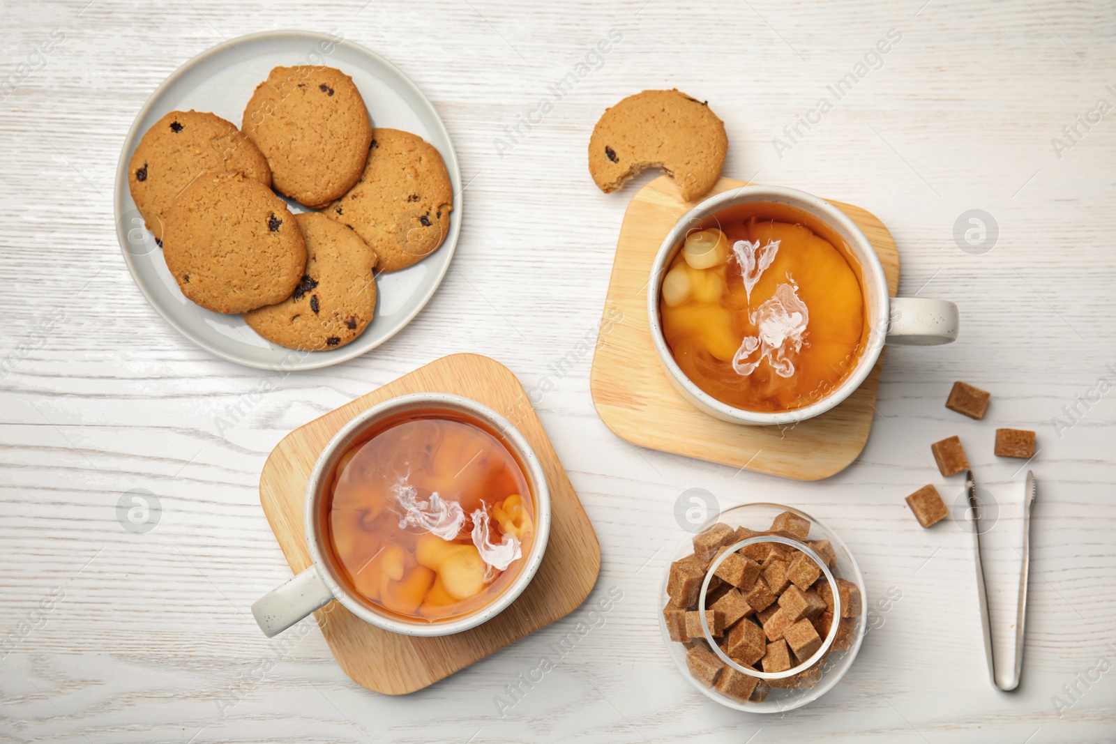 Photo of Flat lay composition with black tea, milk and cookies on wooden table