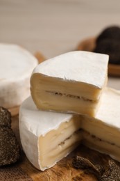Delicious cheese with fresh truffles on wooden table, closeup