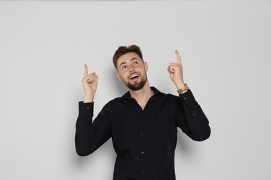 Photo of Handsome man in black shirt pointing at something on light grey background