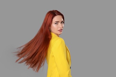 Photo of Stylish woman with red dyed hair on light gray background