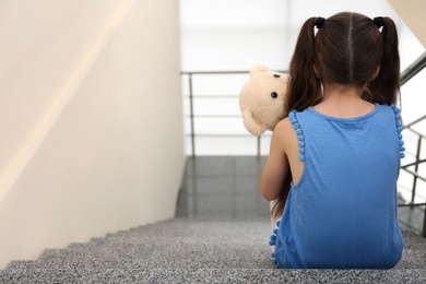 Lonely little girl sitting on stairs. Autism concept