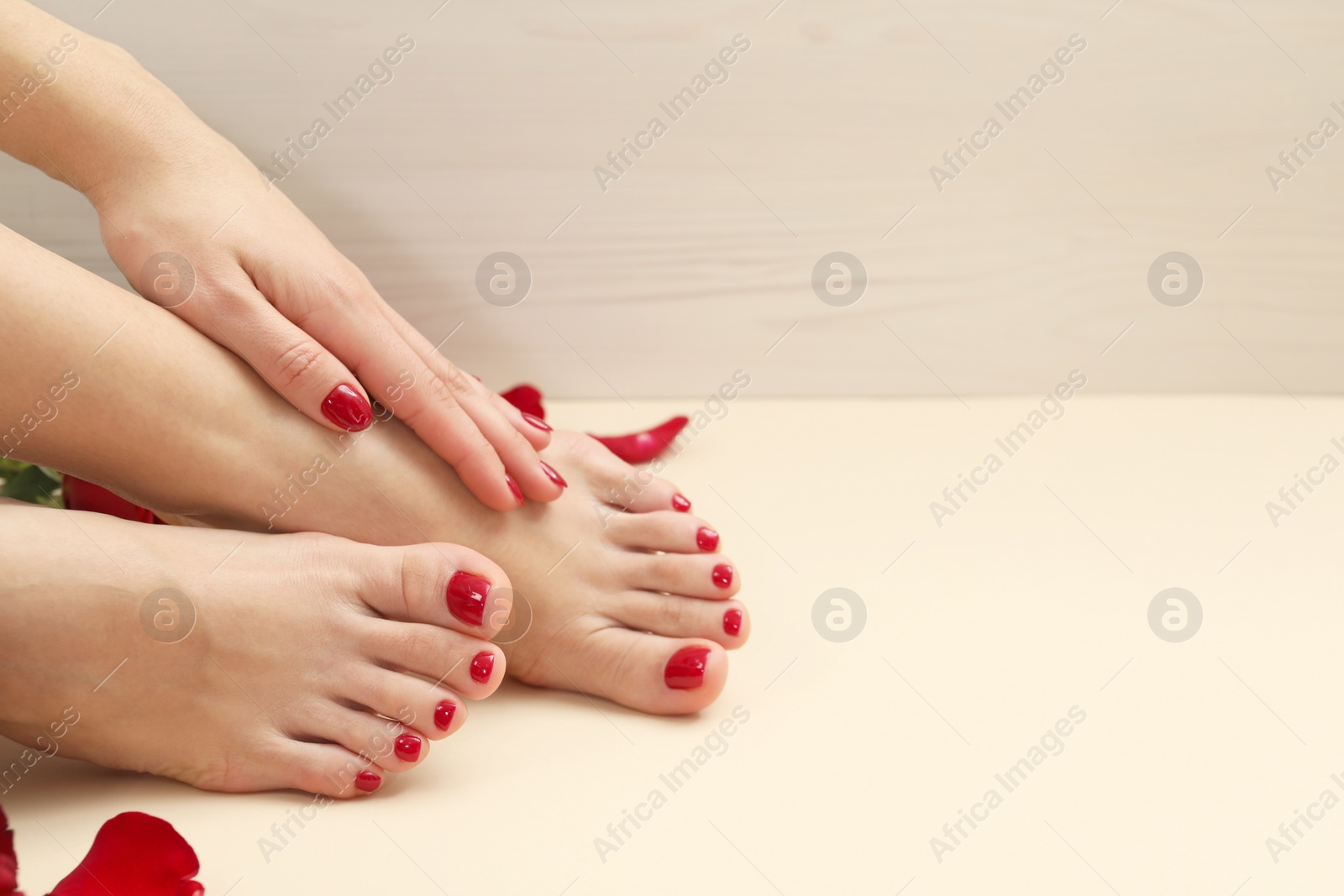 Photo of Woman with stylish red toenails after pedicure procedure on beige background, closeup. Space for text