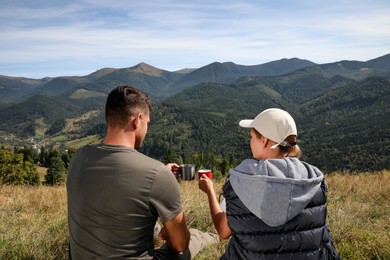 Couple with drink in mountains, back view