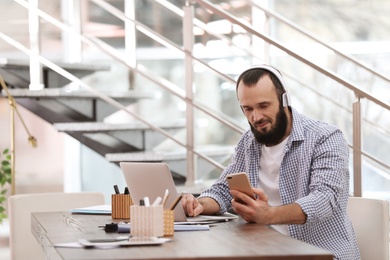 Mature man with headphones and laptop working in home office