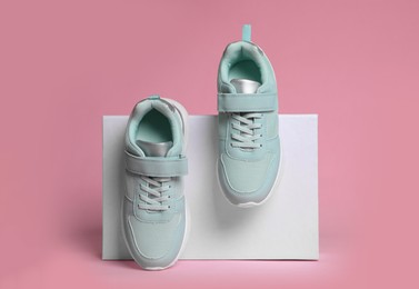 Pair of stylish sneakers and box on pink background