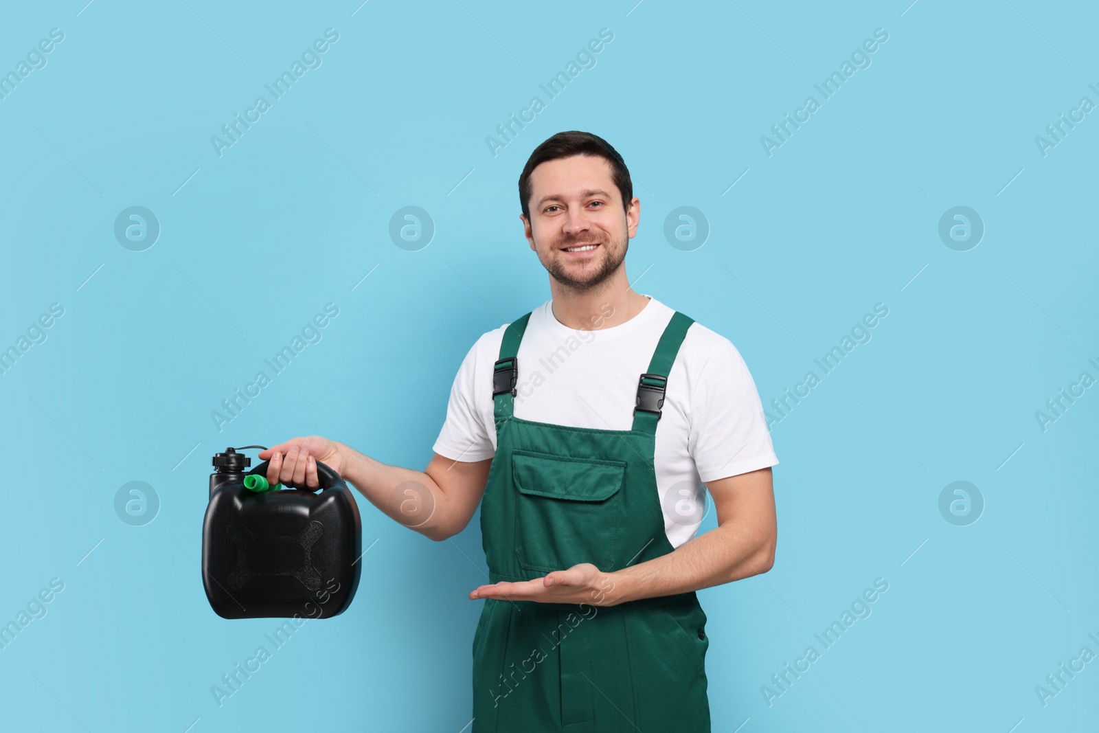 Photo of Handsome man showing black canister on light blue background