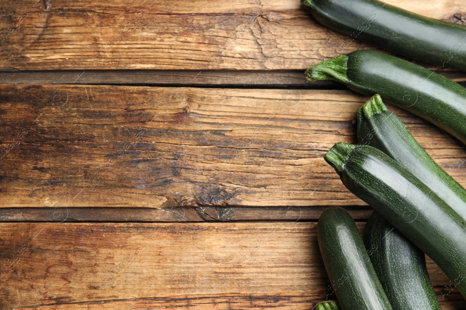 Photo of Green ripe zucchinis on wooden table, flat lay. Space for text