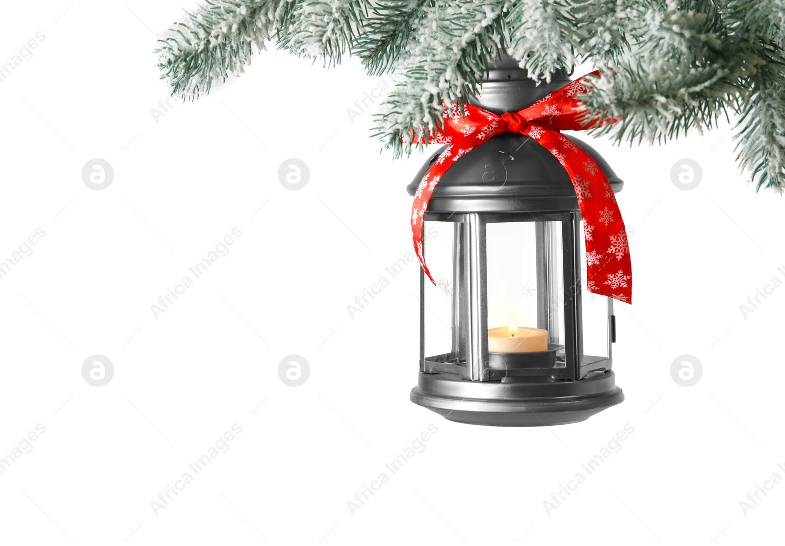 Photo of Christmas lantern with candle hanging on snowy fir tree branch against light background. Space for text