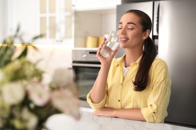 Photo of Young woman drinking pure water from glass indoors, closeup