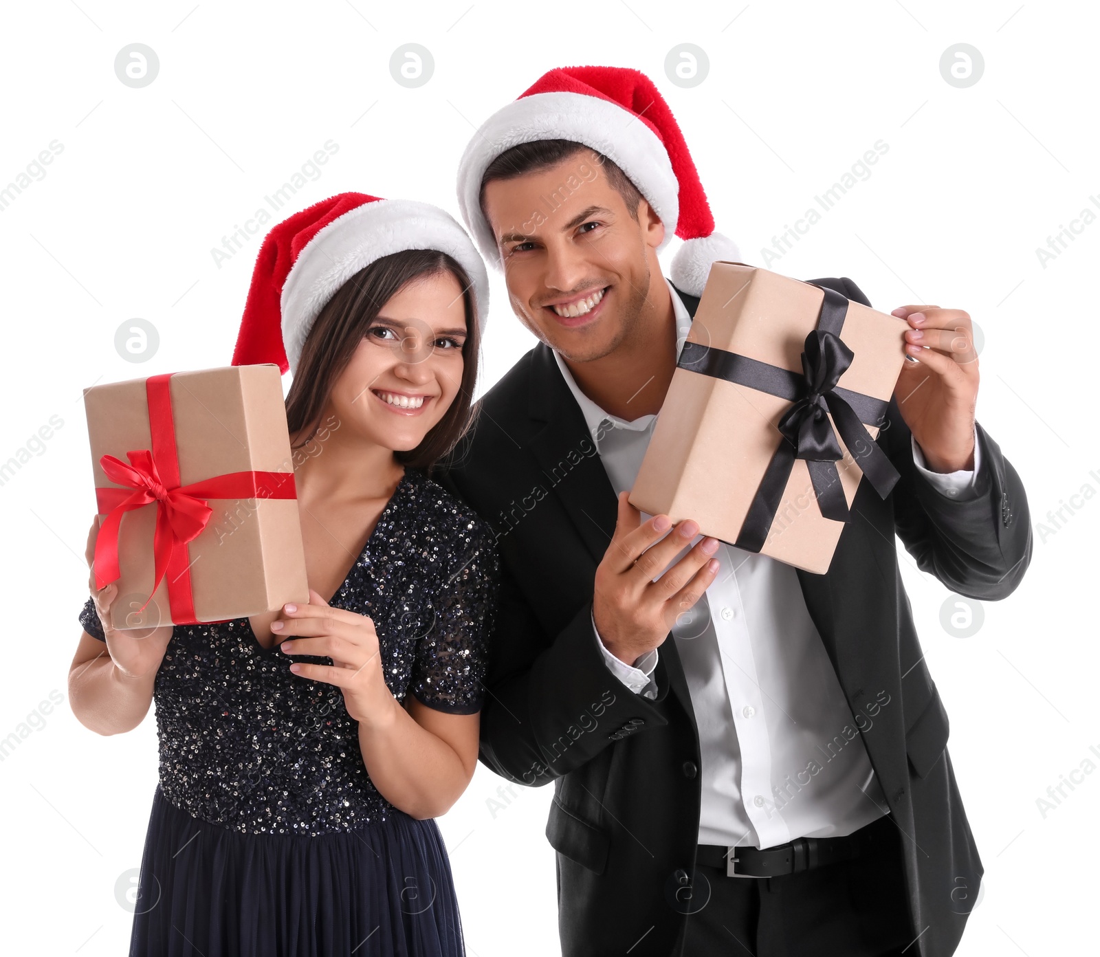 Photo of Beautiful happy couple in Santa hats holding Christmas gifts on white background