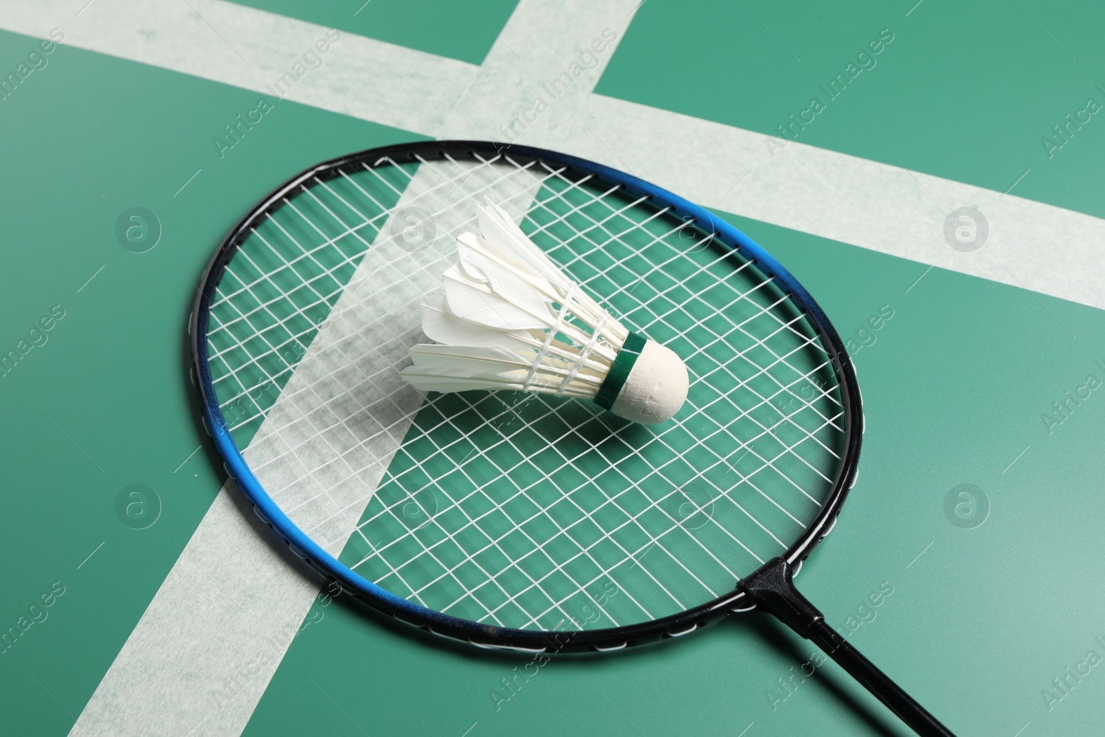 Photo of Feather badminton shuttlecock and racket on green table