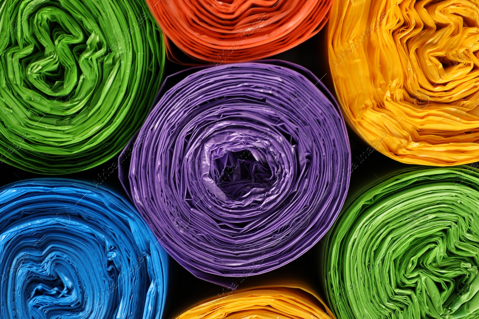 Photo of Rolls of different garbage bags as background, top view