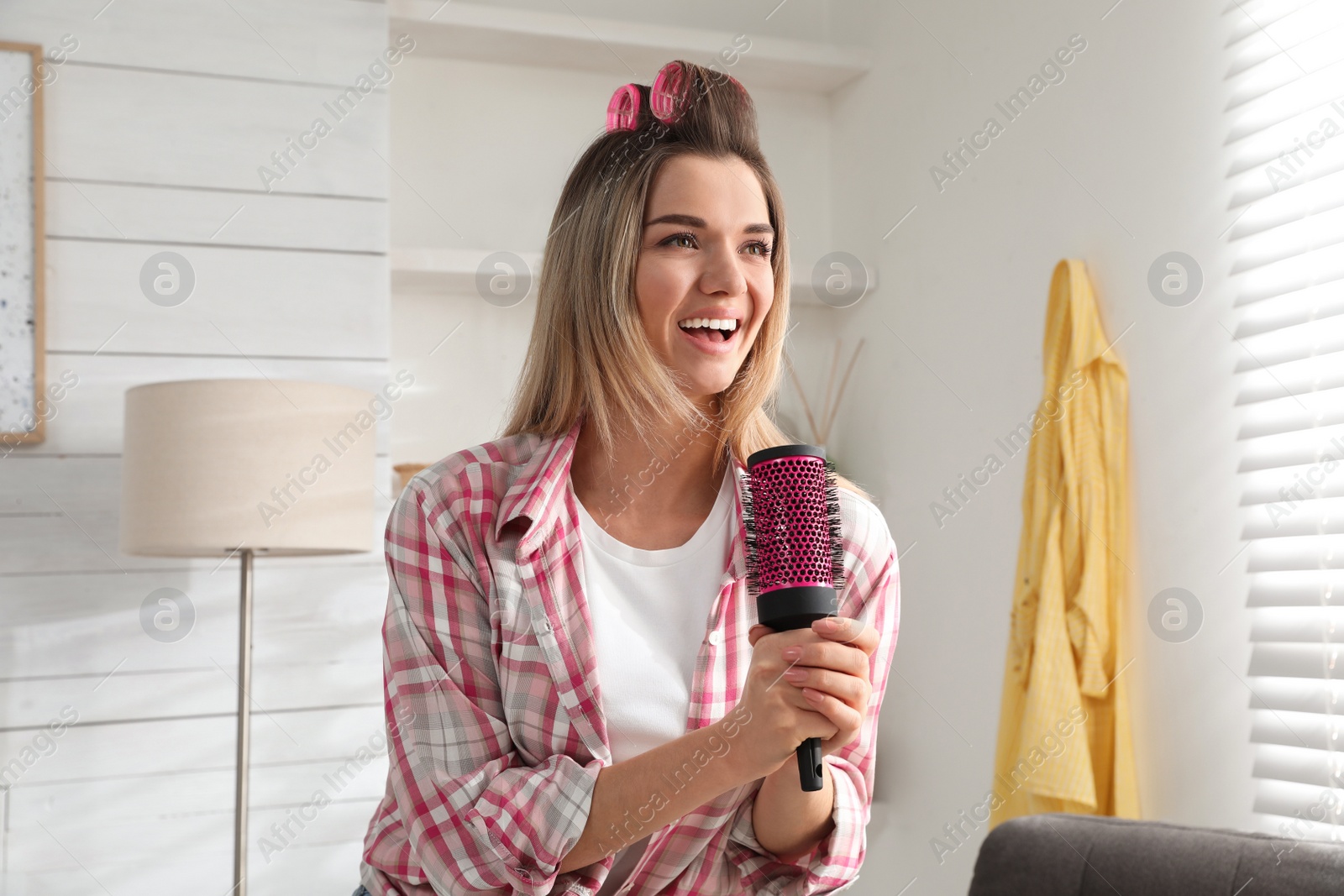 Photo of Woman with hairbrush singing in room at home