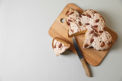 Board with cut delicious Italian Easter dove cake (traditional Colomba di Pasqua) on light grey table, top view. Space for text