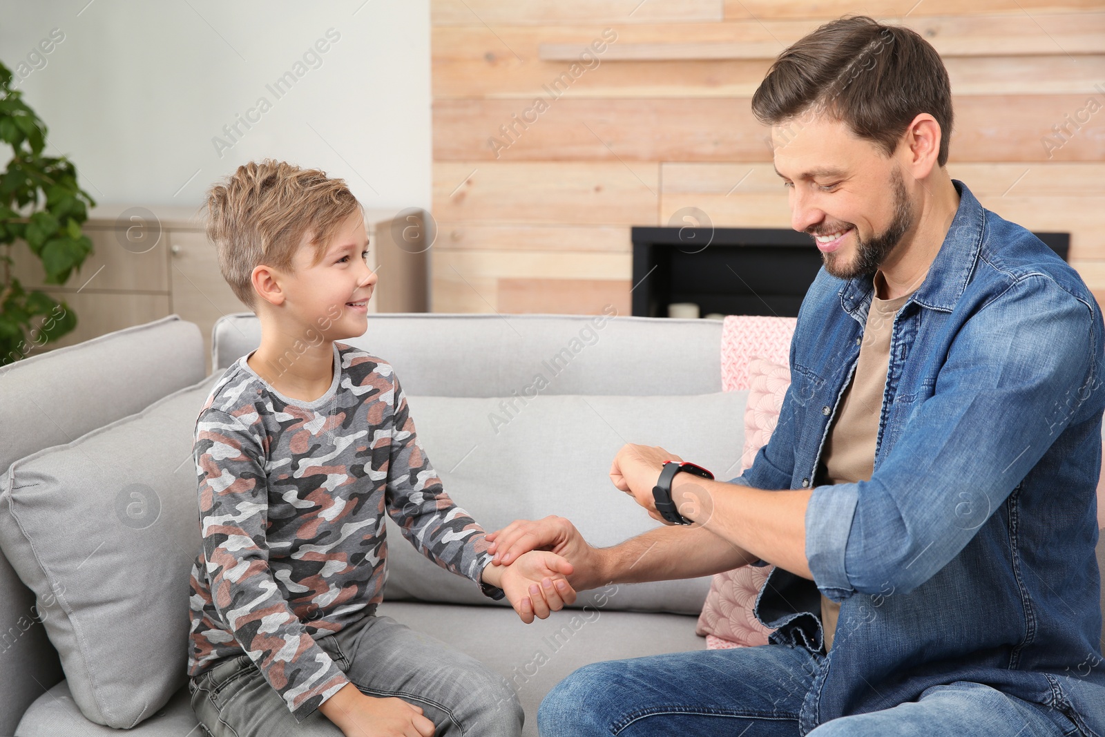 Photo of Man checking little boy's pulse with fingers at home