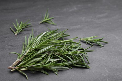 Photo of Sprigs of fresh rosemary on black table, closeup