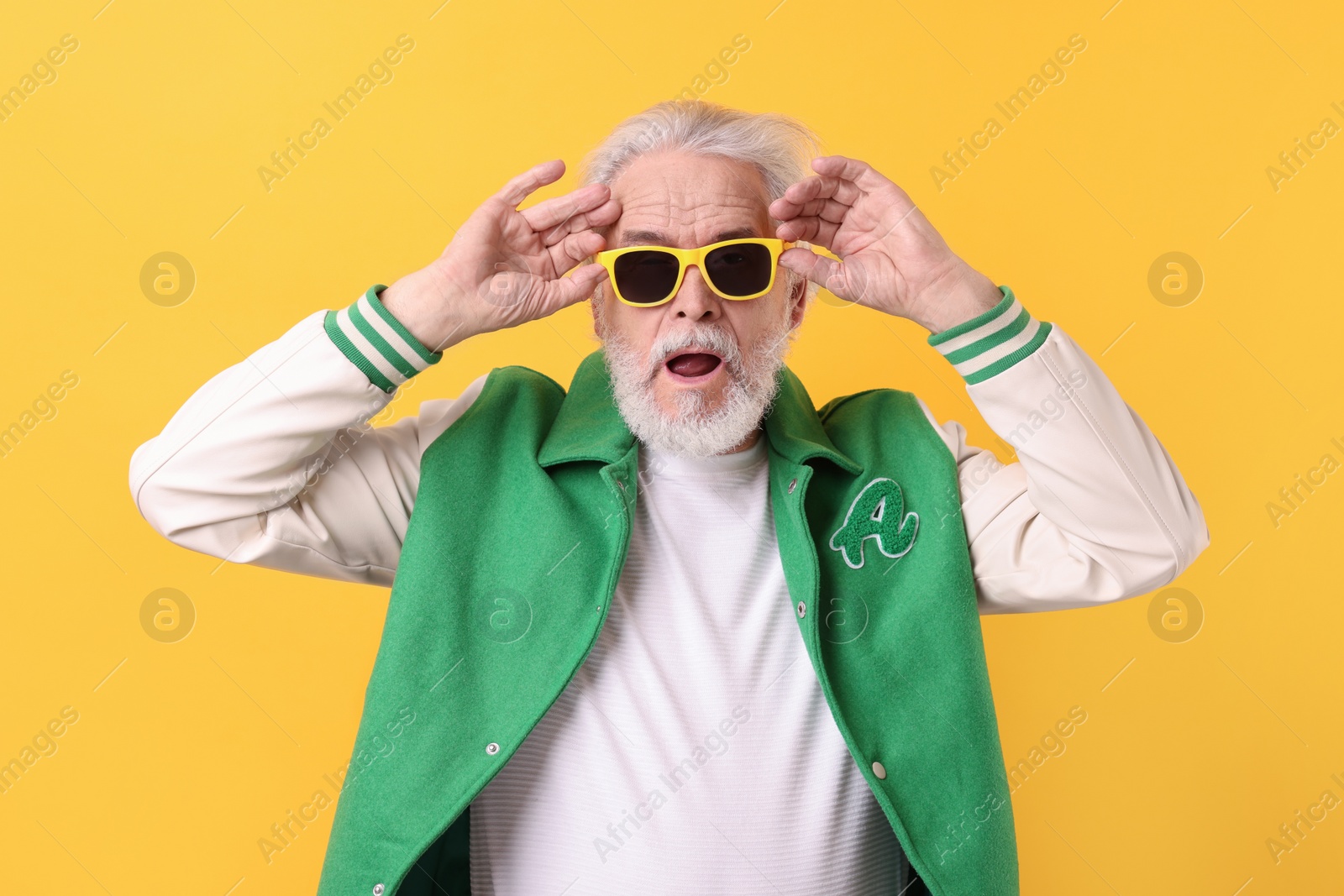 Photo of Portrait of grandpa with stylish sunglasses on yellow background