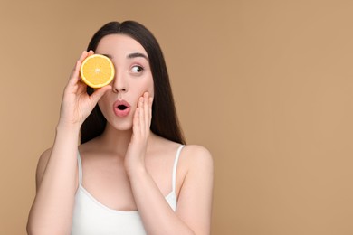 Photo of Emotional young woman with piece of orange on beige background. Space for text
