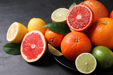 Different citrus fruits on black table, closeup