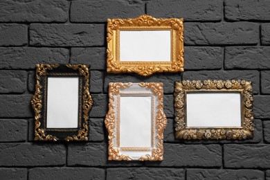 Photo of Empty vintage frames hanging on dark brick wall. Mockup for design