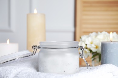 Photo of Jar of natural exfoliating salt scrub on white towel