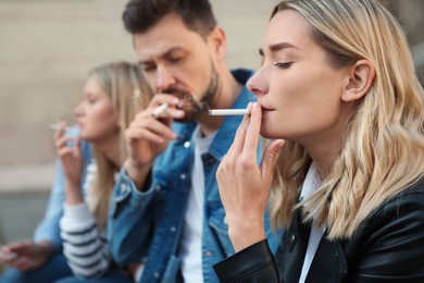 Photo of People smoking cigarettes at public place outdoors, closeup