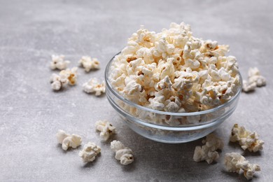 Photo of Bowl of tasty popcorn on grey table, space for text