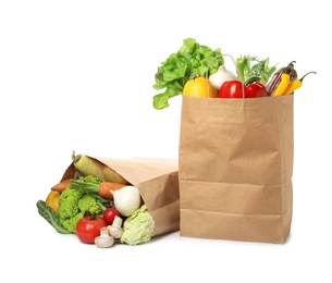 Paper bags with vegetables on white background