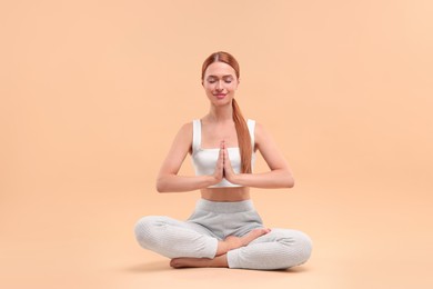 Photo of Beautiful young woman practicing yoga on beige background. Lotus pose