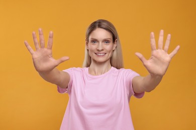 Woman giving high five with both hands on orange background