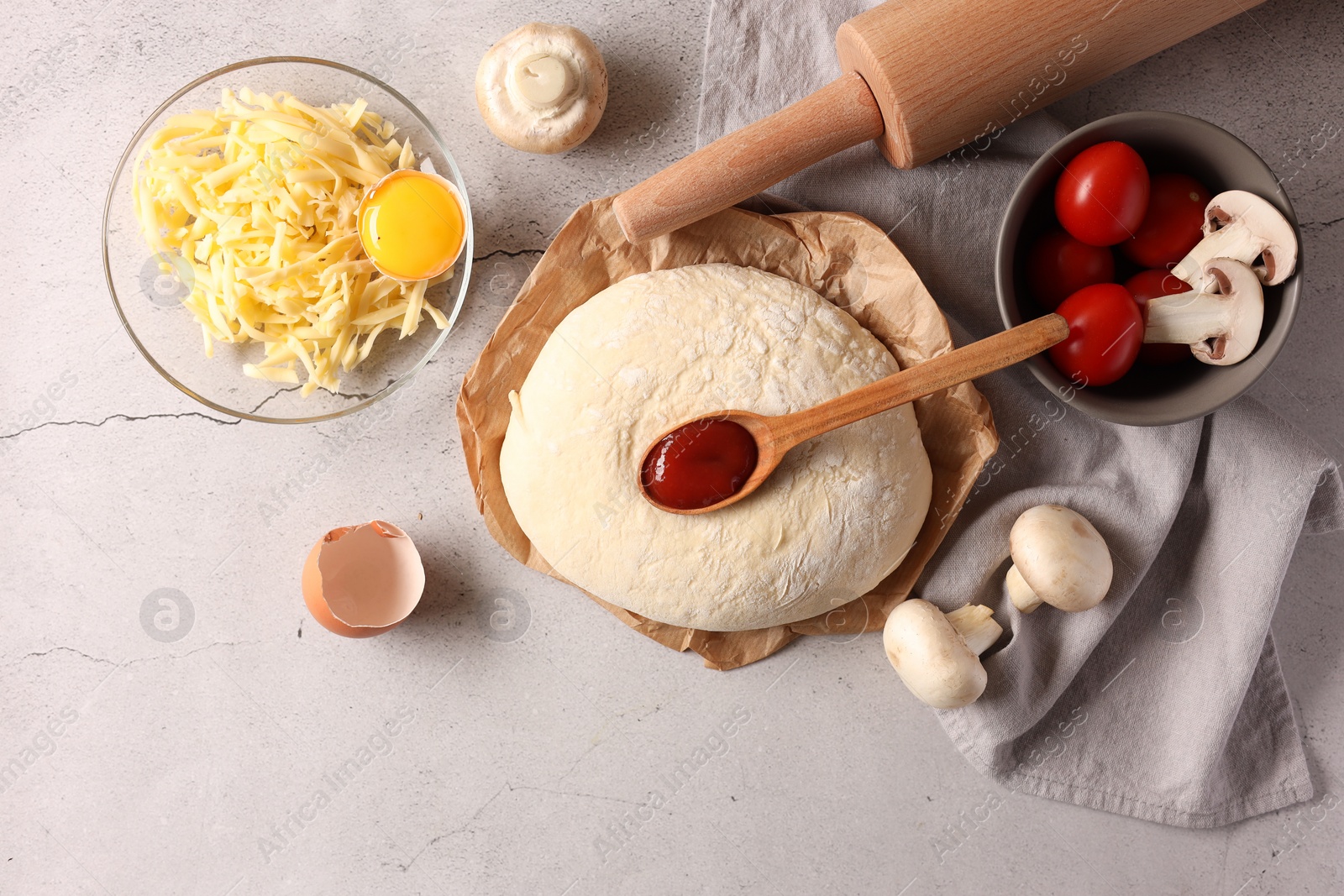 Photo of Pizza dough, products and rolling pin on gray textured table, flat lay