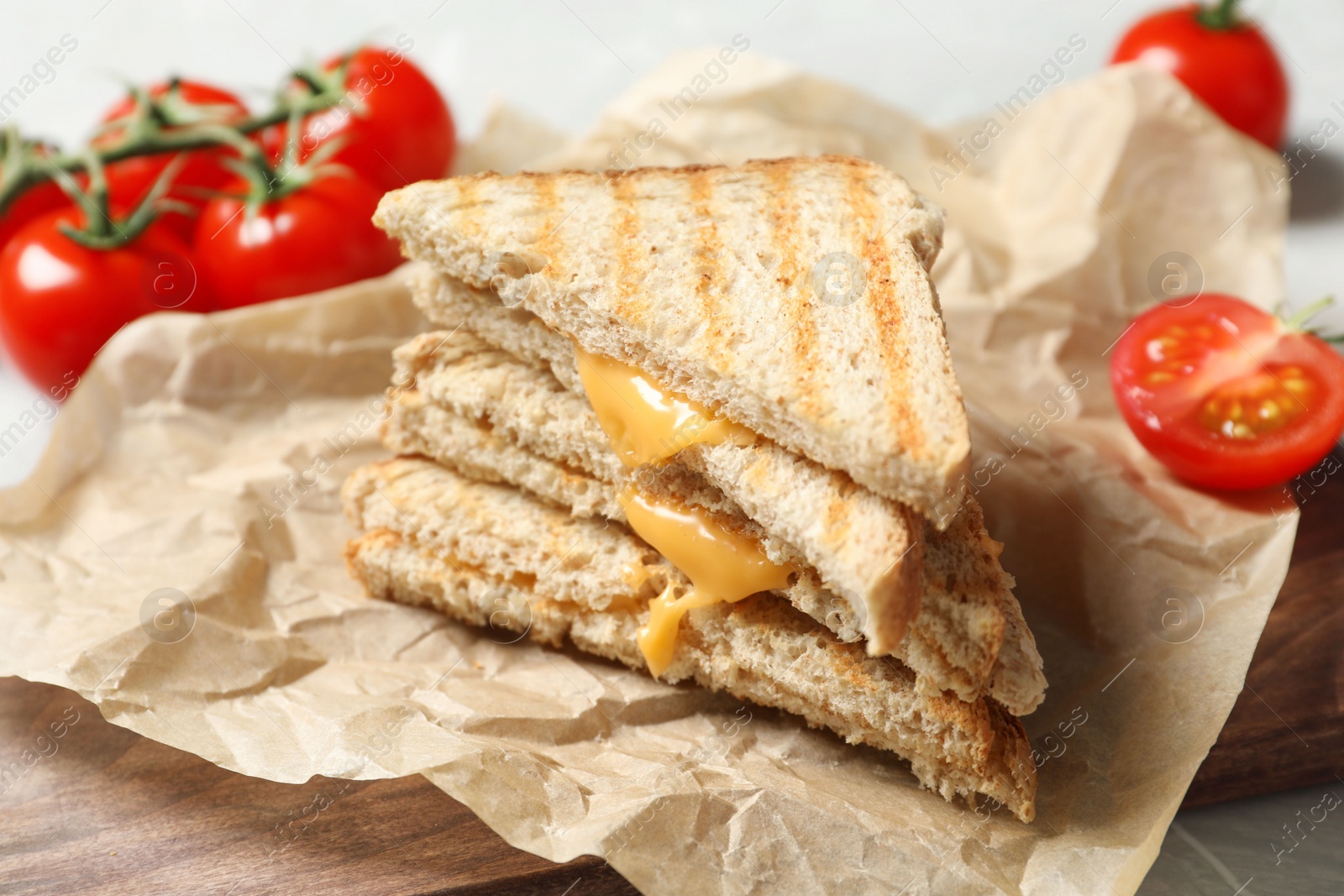 Image of Tasty toast sandwiches with cheese and tomatoes on wooden board, closeup