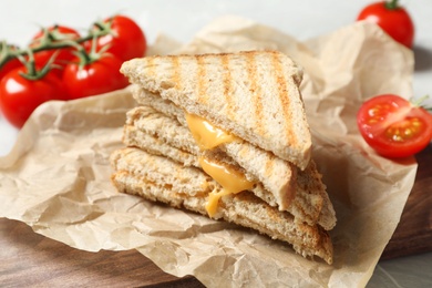 Image of Tasty toast sandwiches with cheese and tomatoes on wooden board, closeup