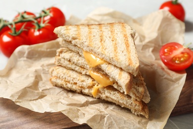 Tasty toast sandwiches with cheese and tomatoes on wooden board, closeup