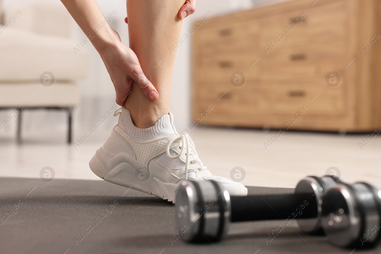 Photo of Woman suffering from leg pain on exercise mat in room, closeup. Space for text
