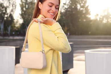 Photo of Fashionable young woman with stylish bag on city street