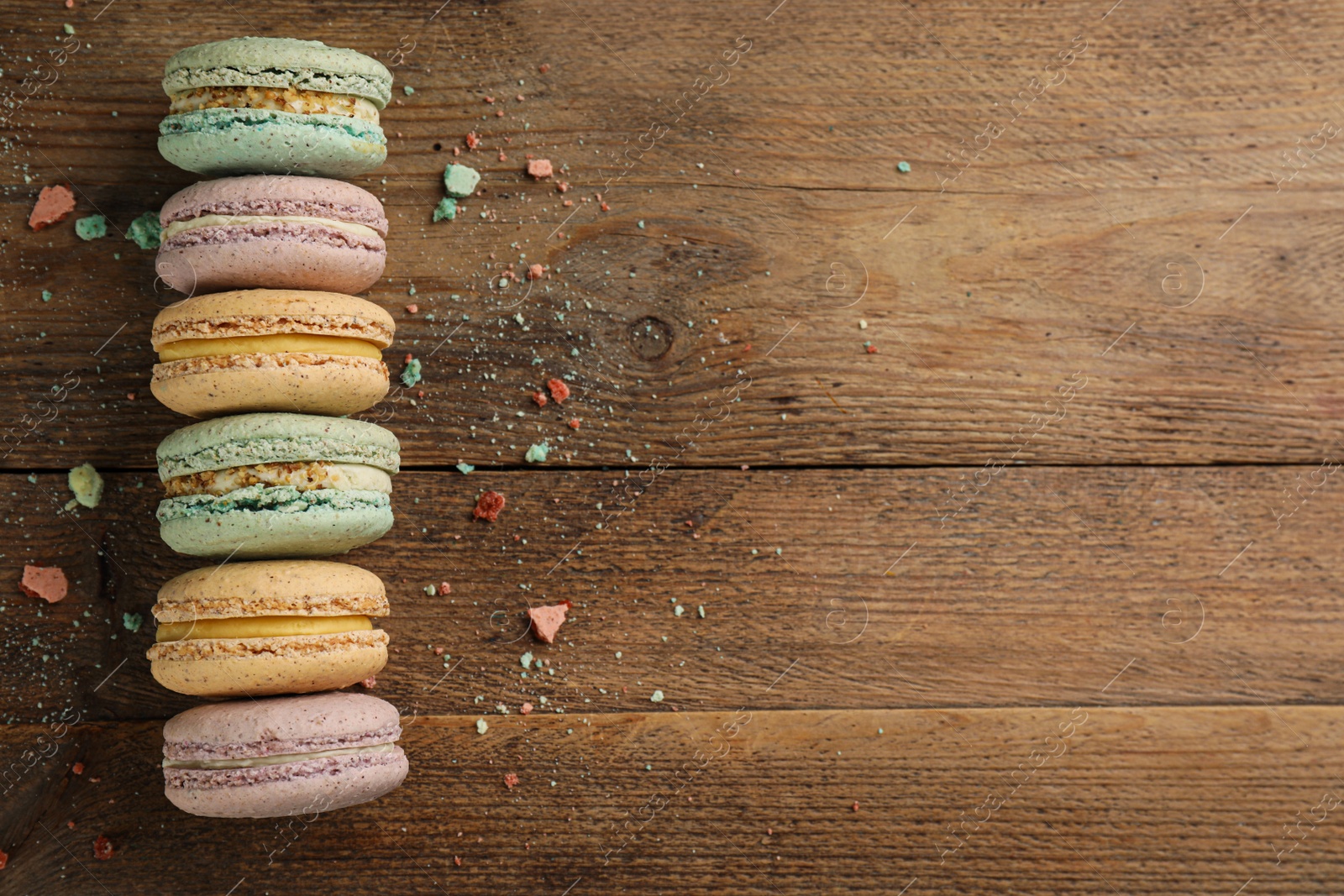 Photo of Different delicious macarons on wooden table, flat lay. Space for text