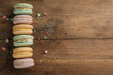 Different delicious macarons on wooden table, flat lay. Space for text