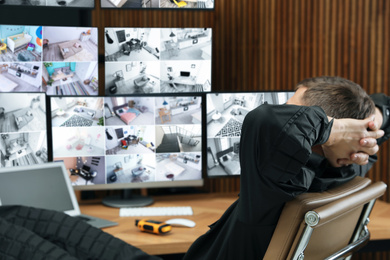 Photo of Tired security guard sleeping at workplace in office