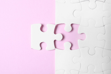 Photo of White puzzle with separated piece on pink background, flat lay