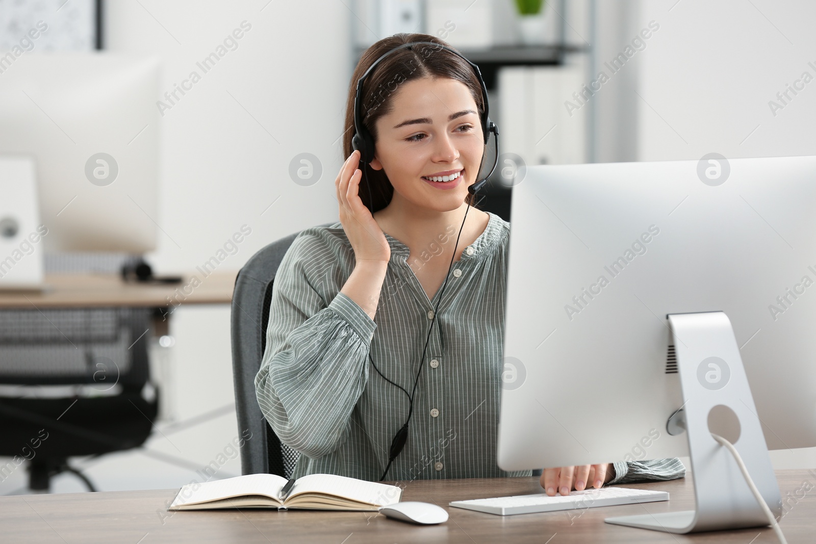 Photo of Hotline operator with headset working on computer in office